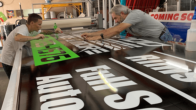 ISL Employees working on vinyl sign